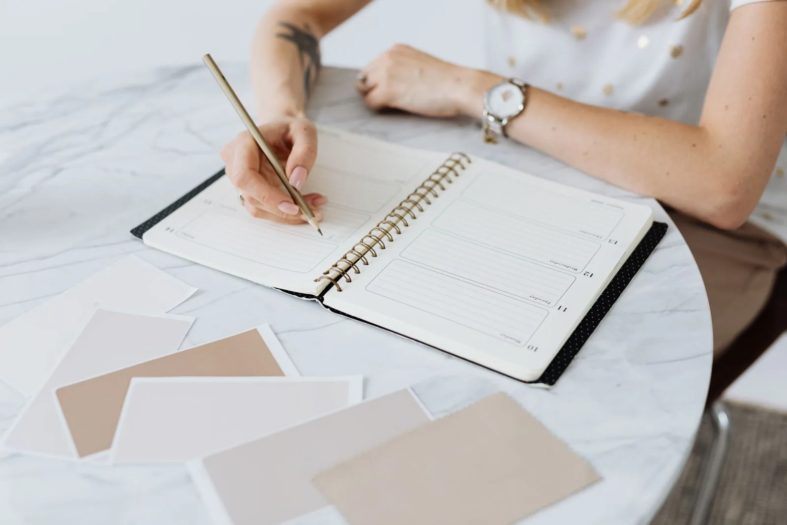 Woman writing in a planner on a marble table, a typical use for erasable pens