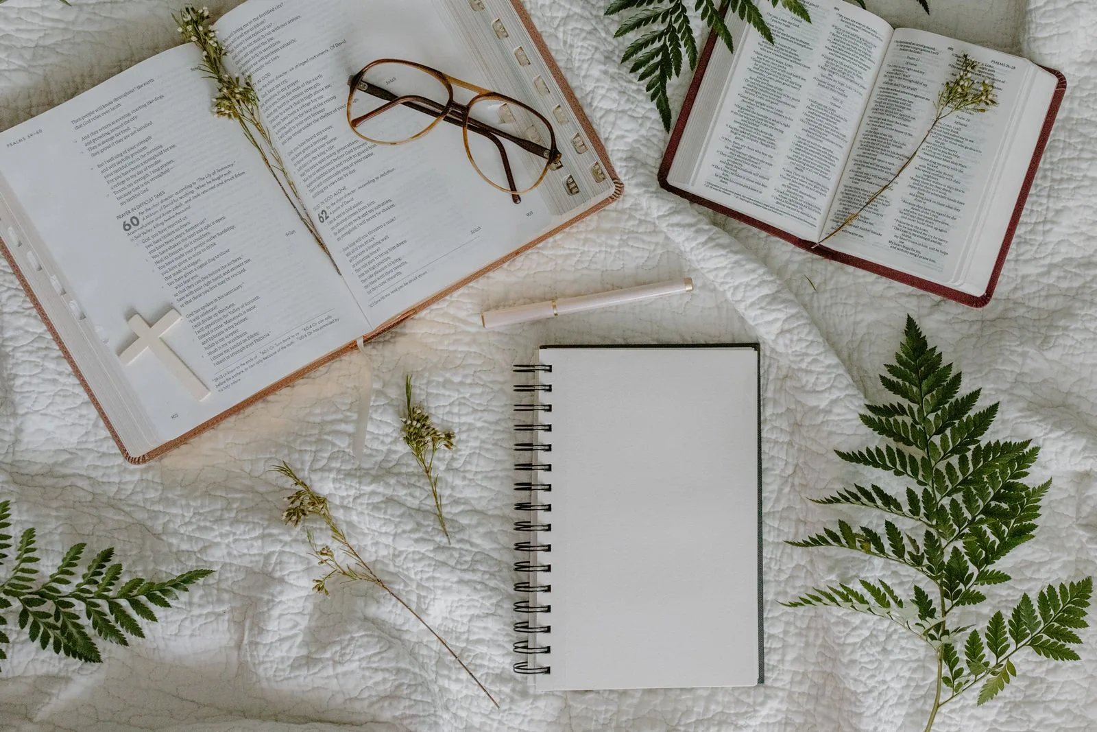 Two open Bibles with a notebook and pen on a quilted surface, set up for Bible journaling